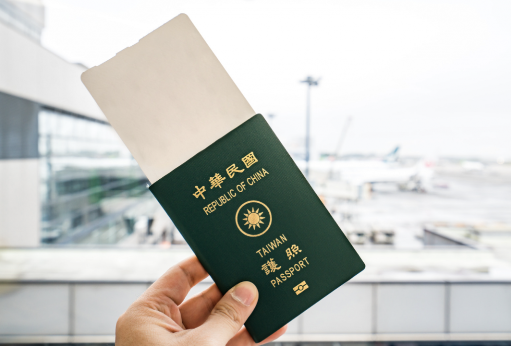 一個男人的手拿著台灣護照在機場拍照，護照夾著機票