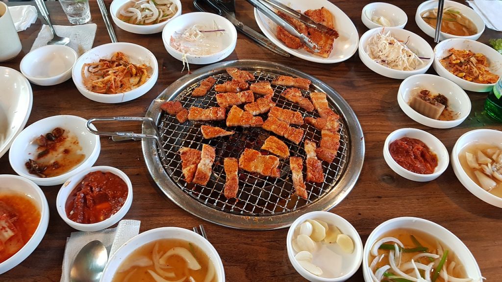 首爾自由行必吃美食,中間正在烤韓式烤肉,豬五花肉,滿滿的韓式小菜在桌上