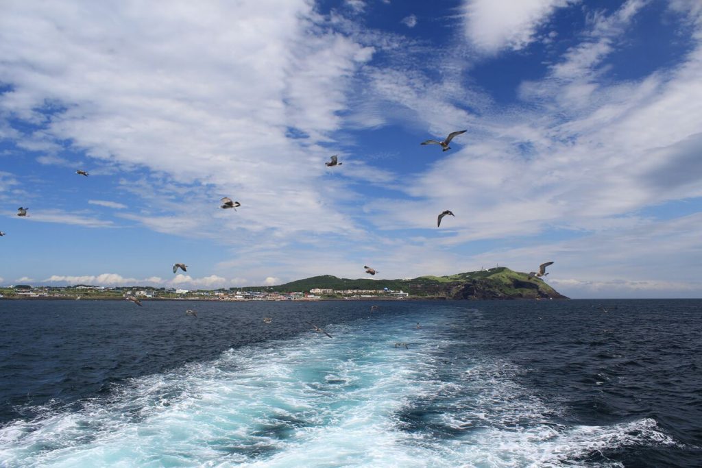 一艘船行駛在海上，看著前方的牛島，濟州島自由行必去景點