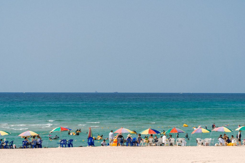 濟州島海邊，許多陽傘與遊客，在海邊放鬆玩耍