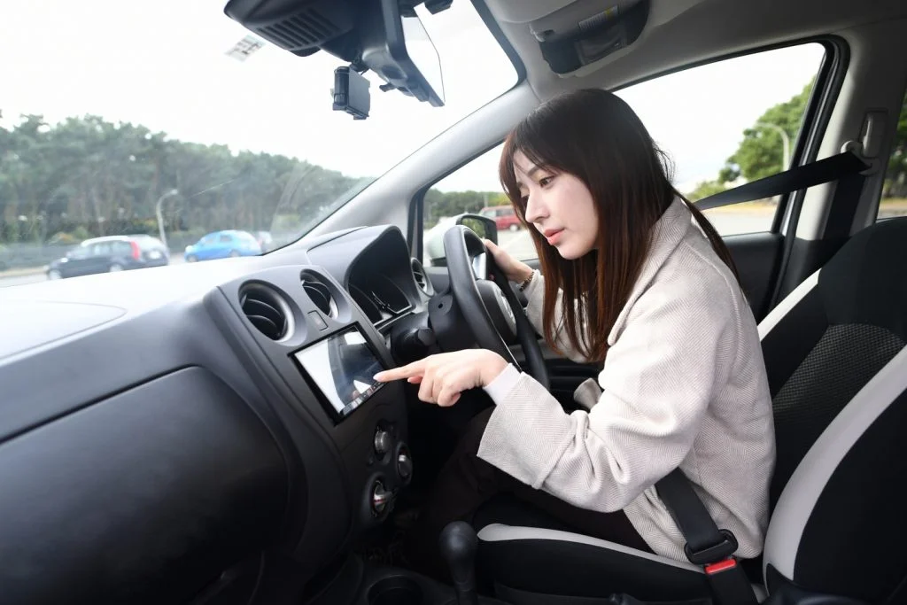 一位日本女性，坐在駕駛座，操作導航系統
