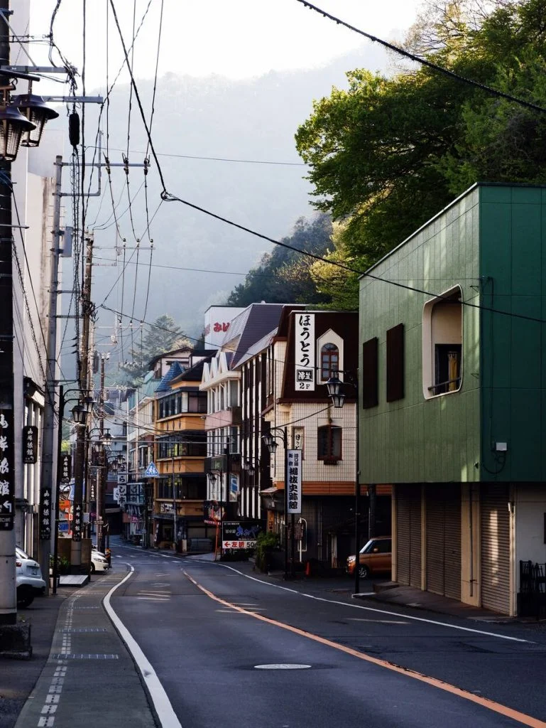 日本街道，路上有著黃色車道分割線，左右兩側是民宅與店家