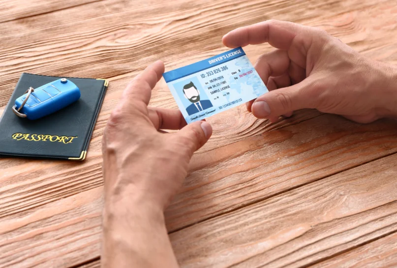 日本租車,必備文件,一個男人的手握著國際駕照,護照,車鑰匙,分別在桌子上