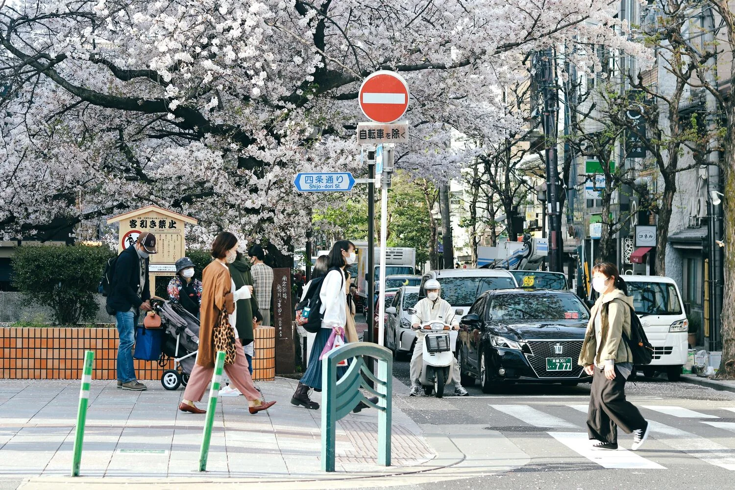 京都街道圖,一台計程車開在路面上,許多路人走在路上,車輛禮讓行人