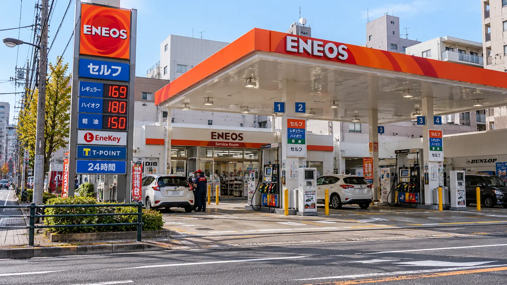 日本街道上的 ENEOS 自助加油站外觀,設有自助加油機與汽油價格看板,顯示三種油品價格